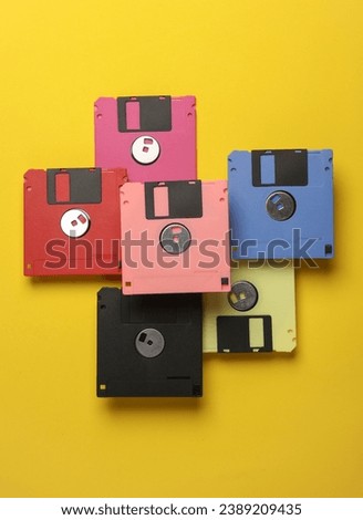 Floating colored retro 80s floppy disks on a yellow background. Conceptual pop, creative layout