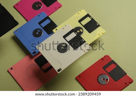 Floating colored retro 80s floppy disks on a green background. Conceptual pop, creative layout