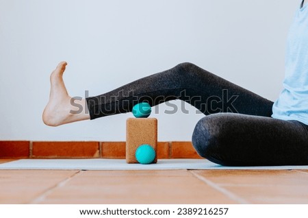 Woman doing calf muscle myofascial release with ball on cork block Royalty-Free Stock Photo #2389216257