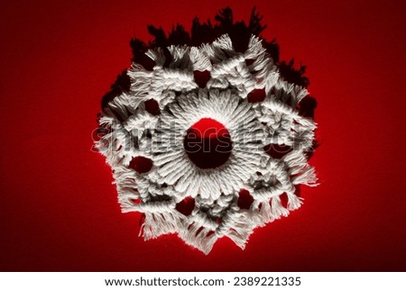 Creative macrame background. Macramé snowflake on the red background. Particular light, conceptual image.