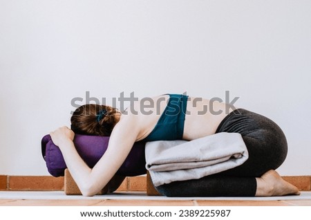 Woman doing restorative yoga child's pose with props Royalty-Free Stock Photo #2389225987