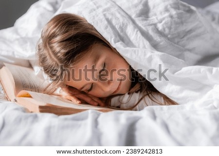 little girl fell asleep with a book under the blanket. High quality photo