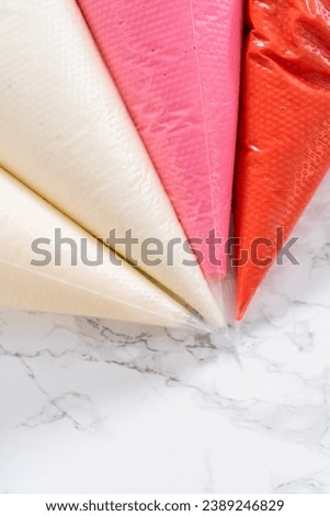 Homemade royal icing in piping bags ready to decorate sugar cookies on the kitchen counter. Royalty-Free Stock Photo #2389246829