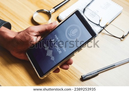 Close up of a man hand holding his smartphone screen showing message how to generate AI voice. Selective focus, generative artificial intelligence voice  cloning concept. Royalty-Free Stock Photo #2389253935