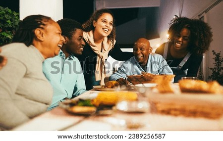 Happy african people eating dinner together at home terrace outdoor - Holidays and family concept - Soft focus on senior woman face