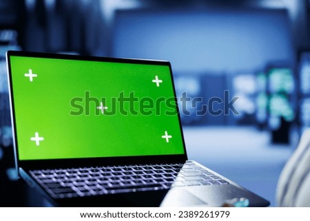 Admin in cloud computing business uses mockup laptop to prevent server machines overload. Expert between rackmounts using green screen device to enable enough network bandwidth for smooth operations