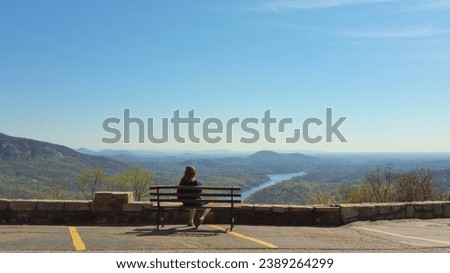 Overlook area with a girl on a bench looking down at the beautiful scenery and lake