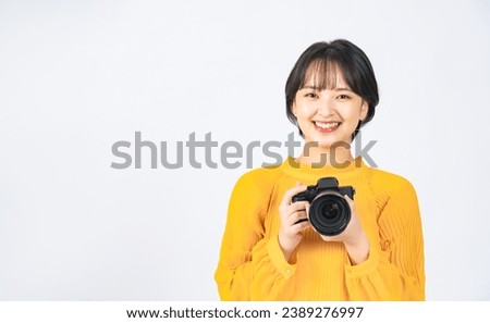 Asian woman wearing casual wear holding digital camera. Girl photographer. Royalty-Free Stock Photo #2389276997