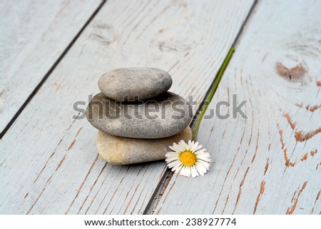Three zen stones on old wood with daisies
