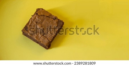Panoramic picture of a dark chocolate brownie on yellow dish.