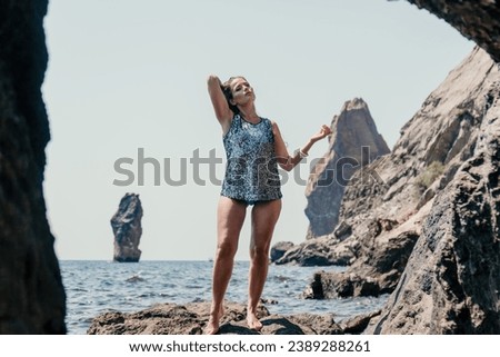 Woman summer travel sea. Happy tourist enjoy taking picture outdoors for memories. Woman traveler posing on the beach at sea surrounded by volcanic mountains, sharing travel adventure journey