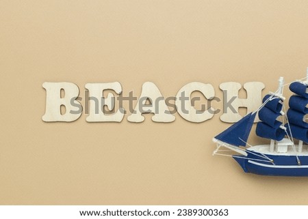 Blue sailboat and the inscription beach on a beige background. The concept of a holiday on the coast.