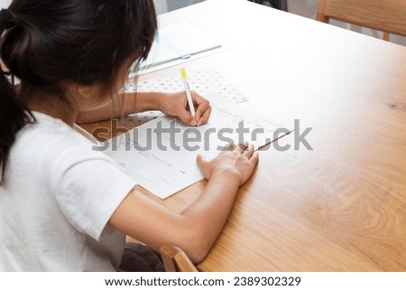 A girl doing homework at her desk.
Translation:3-digit addition, subtraction, month and date, calculation, word problems, How much does it cost to buy an 88 yen apple and 75 yen at a store? ,answer
