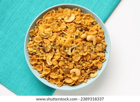 Indian snacks corn flakes mixture serve in bowl isolated on white and blue table matt background  Royalty-Free Stock Photo #2389318337