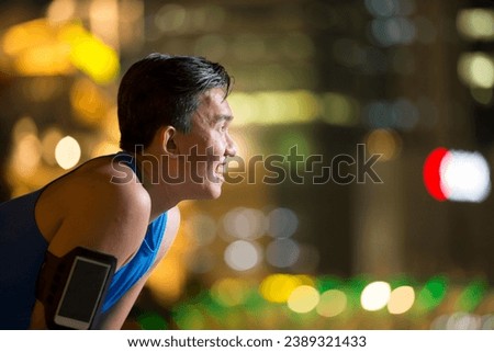Athlete Chinese man outdoors in urban city at night. Male fitness concept. Royalty-Free Stock Photo #2389321433