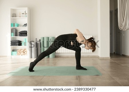 Young attractive woman practicing yoga indoors.  Woman practice in in fitness club. Yoga concept. Lifestyle.