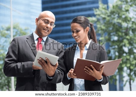 Two Indian business people with digital tablet in a modern urban setting. Royalty-Free Stock Photo #2389339731