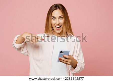 Full body young woman she wear shirt white t-shirt casual clothes hold in hand use point finger on mobile cell phone isolated on plain pastel light pink background studio portrait. Lifestyle concept