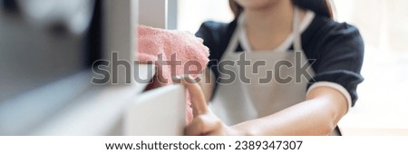 Housewives use towels to wipe things, tables, chairs, Housework, Daily routine ,Removes germs and dirt and deep stains, Spray alcohol, Clean up on weekends. Royalty-Free Stock Photo #2389347307