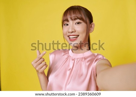 Attractive girl taking selfie with finger heart sign, smiling happy, with stretched out hand Royalty-Free Stock Photo #2389360609