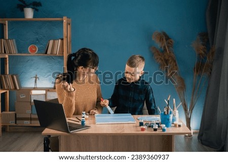 Online education of children. Mother and her son watching a video lesson or creative course art drawing using laptop computer at home. Copy space