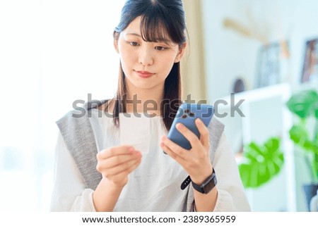 Young woman holding a receipt and smartphone Royalty-Free Stock Photo #2389365959