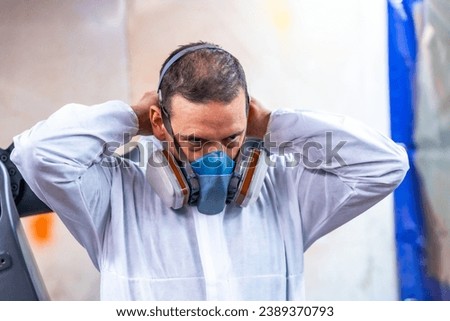Close-up photo of an industrial painter putting on protective gear for work Royalty-Free Stock Photo #2389370793