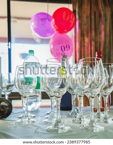 60th birthday balloons hanging from the window, selective focus on wine glasses on the table. Birthday celebration. Vertical format.