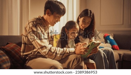 Close Up of a Korean Family Spending Time Together, Using Digital Tablet Computer at Home. Young Parents Helping Their Daughter Solve a Question in an Educational Game. Supportive Parenting Concept Royalty-Free Stock Photo #2389386953