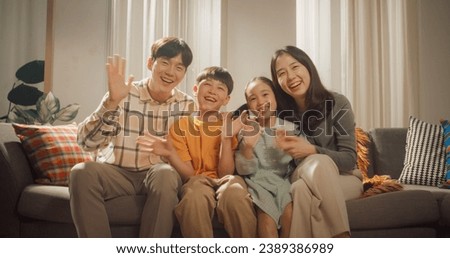 Portrait of a Happy Korean Family in the Living Room at Home, Smiling and Waving at the Camera. Screen Replacement for Video Call With Family and Friends. Heartwarming Shot of Friendly People Royalty-Free Stock Photo #2389386989