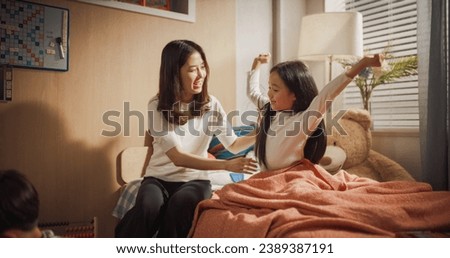 Beautiful Korean Mother Enters Children's Room. Little Son is Playing with Toys, Daughter is Waking Up, Stretching Her Arms in a Cute Way. Lovely Asian Family Ready to Spend Sunny Day Together Royalty-Free Stock Photo #2389387191