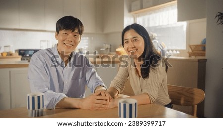 Attractive Korean Young Couple Sitting at Home, Talking. Boyfriend and Girlfriend Having Fun Conversations in the Kitchen. Family with Healthy Lifestyle Looking at Camera and Smiling
