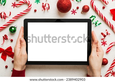 Christmas online shopping from home, female hands holding tablet pc with blank white display top view. woman hand holding tablet with blank screen, Christmas tree and gifts on background.