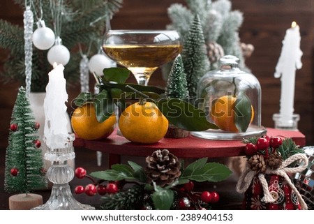 A glass of champagne and tangerines on the table. Christmas and New Year background decorated with Christmas trees
