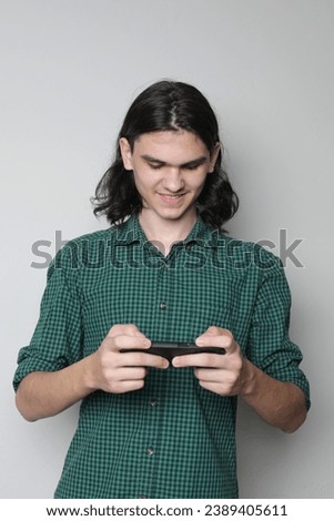 Smiling teen standing and using mobile. Teenager checking apps on mobile device or playing mobile games on the phone.