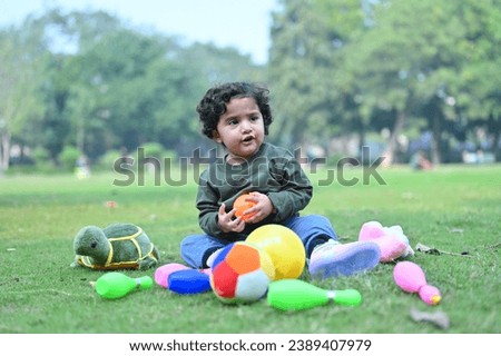 happy beautiful child playing in the ground with toys and trees in winter.