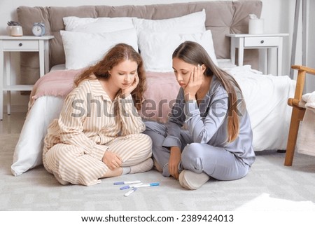 Young lesbian couple with pregnancy tests in bedroom
