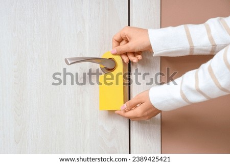 Woman with door hanger in hotel room, closeup