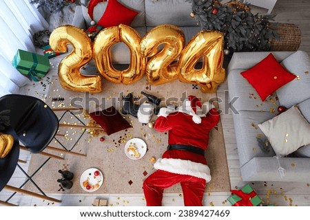 Drunk Santa Claus lying in messy living room after New Year party, top view Royalty-Free Stock Photo #2389427469
