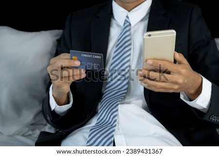 Businessman hand hold mock-up credit card for online shopping on smartphone from hotel bedroom, payment e-commerce, internet finance bank, spend money electronic wallet.
