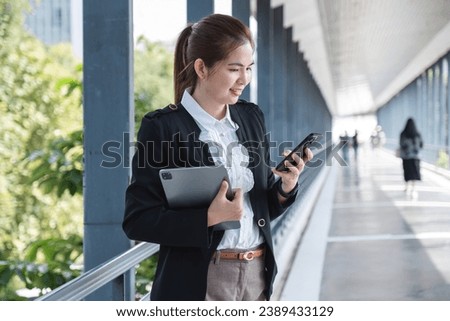Asian businesswoman holding a tablet checking company work Confident female employee with tablet stands in front of camera on city background on skywalk