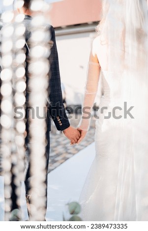 The bride and groom holding hands at the wedding ceremony venue. Wedding decor. professional organization of the celebration. happy newlyweds. selective focus
