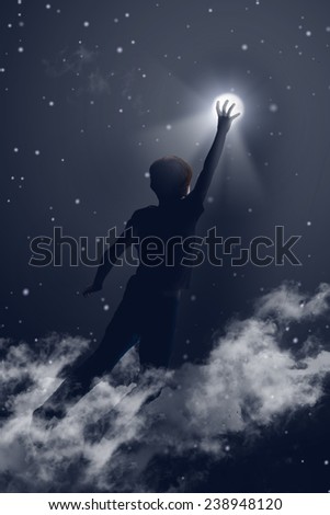 Image of little boy reaching the moon in night's sky