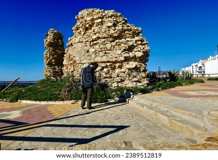 A curious tourist taking picture of ancient little tower in a beach in Nerja Spain