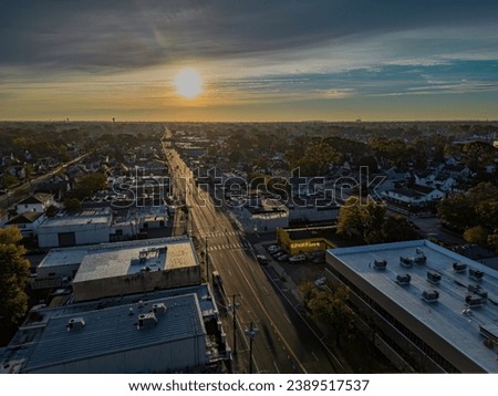 A high angle, aerial shot of a long road, reflecting the sun after a cloudy sunrise on Long Island, New York. Royalty-Free Stock Photo #2389517537