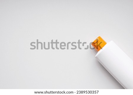 Beauty product in white plastic bottle with orange cap on white background. 