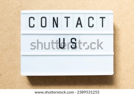 Lightbox with word contact us on wood background