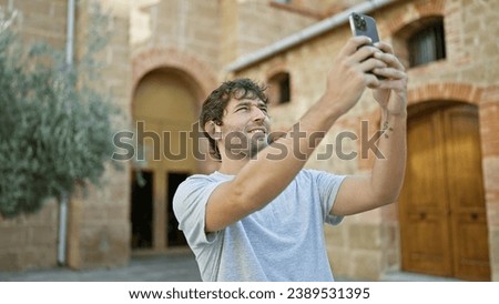 Handsome bearded young man making cool lifestyle selfie with smartphone in city park
