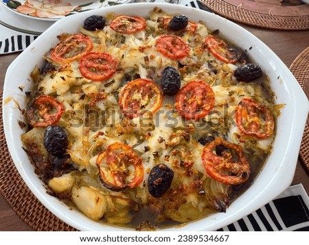 Cod with potatoes , olives , tomatoes and olive oil.