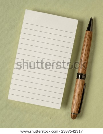 blank sheet of ruled paper in a small journal with a luxury pen against textured art paper